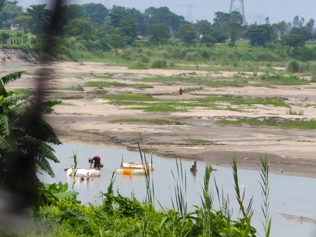 Bangladeshi residents collect sand and boulders from the Mahananda River, across the fence, within India’s boundary pillars.